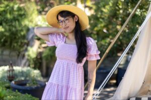 An FFS patient smiling with a light pink dress and sun hat